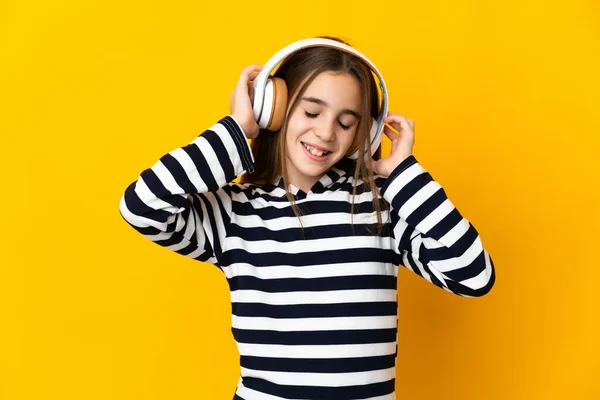 小さな女の子孤立した上の黄色の背景リスニング音楽 — ストック写真