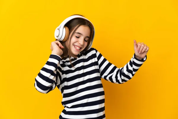 小さな女の子孤立した上に黄色の背景リスニング音楽とダンス — ストック写真