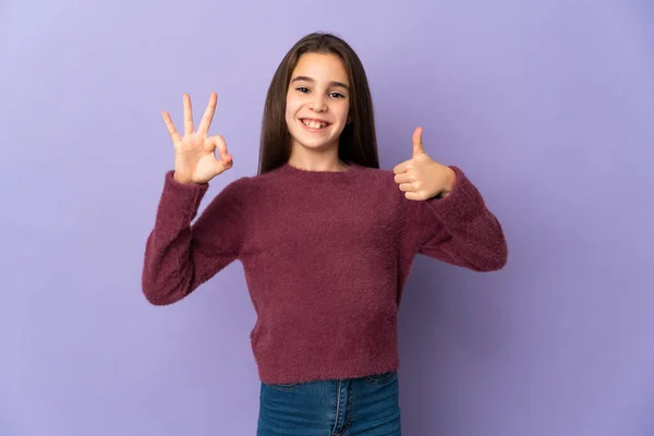 女の子孤立した上に紫色の背景ショーOk Signと親指アップジェスチャー — ストック写真