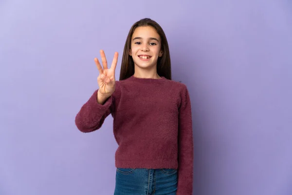被紫色背景隔离的小女孩快乐地数着三根手指 — 图库照片