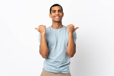 Afro-Amerikalı bir adam beyaz arka planda. Baş parmakları havada ve gülümsüyor.