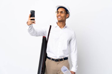 African American architect man with helmet and holding blueprints over isolated white background _ making a selfie