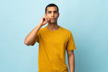 Tecrit edilmiş arka planda kalan Afrikalı Amerikalı bir adam sessizlik işareti gösteriyor.