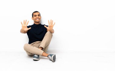 African American man sitting on the floor counting ten with fingers