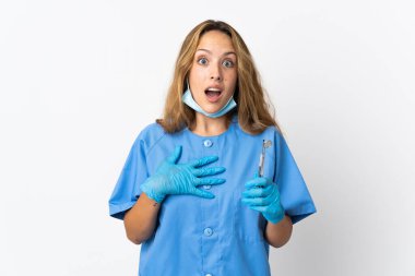 Woman dentist holding tools isolated on white background surprised and shocked while looking right