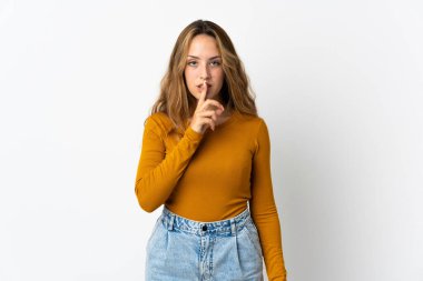 Mavi arka planda izole edilmiş genç sarışın bir kadın sessizlik işareti gösteriyor. Parmağını ağzına sokuyor.