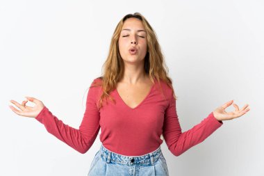 Zen pozunda mavi arka planda izole edilmiş genç sarışın kadın.