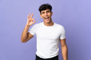 Arjantinli genç adam arka planda izole edilmiş. Parmaklarıyla işaret veriyor.