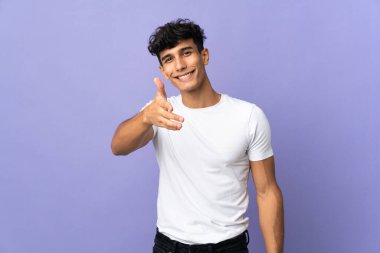 Young Argentinian man isolated on background shaking hands for closing a good deal