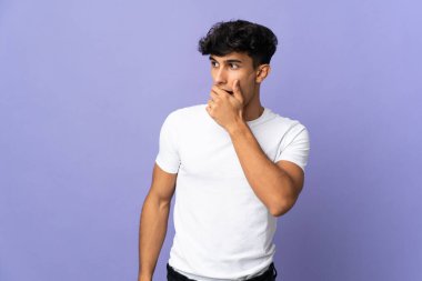 Arjantinli genç adam arka planda izole edilmiş. Yan tarafa bakarken sürpriz jest yapıyor.