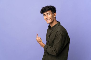 Young Argentinian man isolated on background pointing back