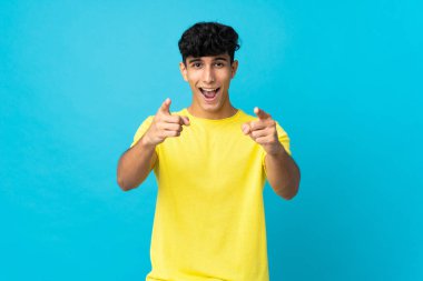 Arjantinli genç adam arka planda izole edilmiş şaşırmış ve ön tarafı işaret ediyor.