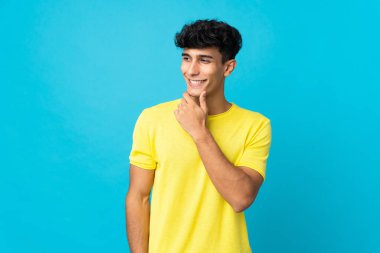 Arjantinli genç adam arka planda izole edilmiş, yana bakıyor ve gülümsüyor.