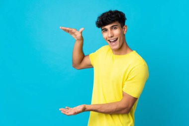 Arjantinli genç bir adam arka planda izole edilmiş bir ilan vermek için kopyalama alanı tutuyor.