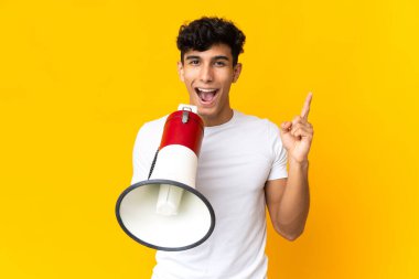 Sarı arka planda izole edilmiş genç Arjantinli bir adam megafonla bağırıyor ve işaret ediyor.
