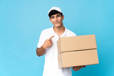 Arjantinli adam mavi arka planda izole edilmiş bir şekilde bir ürün sunmak için kenarı işaret ediyor.