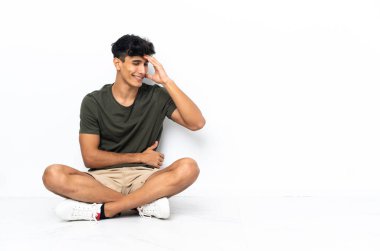 Genç Arjantinli adam yerde oturmuş gülüyor.