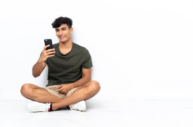 Young Argentinian man sitting on the floor making a selfie
