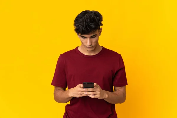 Młody Argentyńczyk Odizolowany Żółtym Tle Przy Użyciu Telefonu Komórkowego — Zdjęcie stockowe