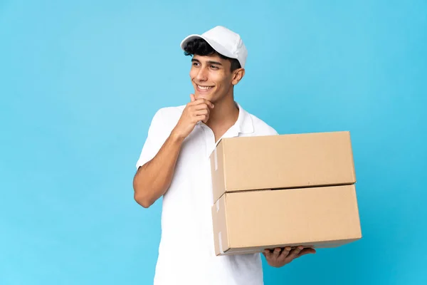 Entrega Homem Argentino Isolado Fundo Azul Olhando Para Lado Sorrindo — Fotografia de Stock