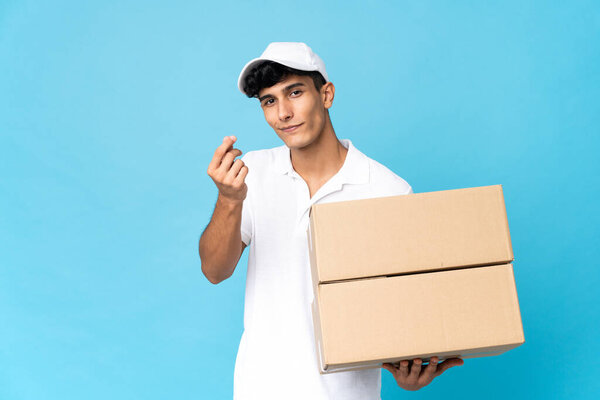 Delivery Argentinian man isolated on blue background making money gesture