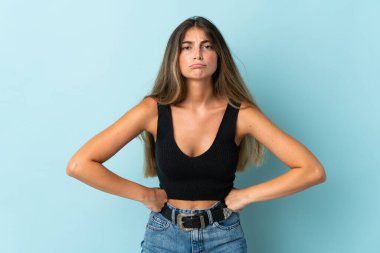 Kafkasyalı genç bir kadın mavi arka planda izole edilmiş, kızgın.