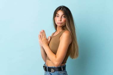 Kafkasyalı genç bir kadın mavi arka planda bir şeyler planlıyor.