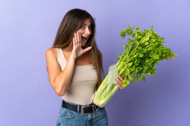 Mor arka planda izole edilmiş bir kereviz tutan genç kadın bir şeyler fısıldıyor.