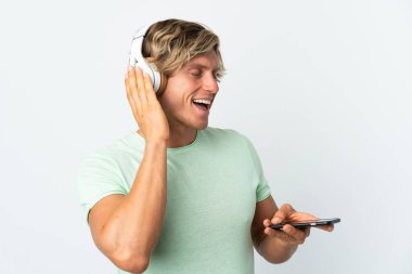 İngiliz adam izole edilmiş beyaz arka planda müzik dinliyor ve şarkı söylüyor.
