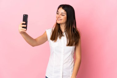 Pembe arka planda izole edilmiş beyaz bir kadın selfie çekiyor.