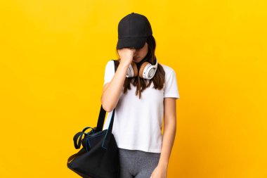 Spor çantalı genç bayan sarı arka planda baş ağrısı ile izole edildi.