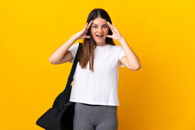 Young sport woman with sport bag isolated on yellow background with surprise expression