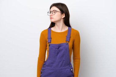 Mavi arka planda izole edilmiş genç Rus kadın yan tarafa bakıyor.