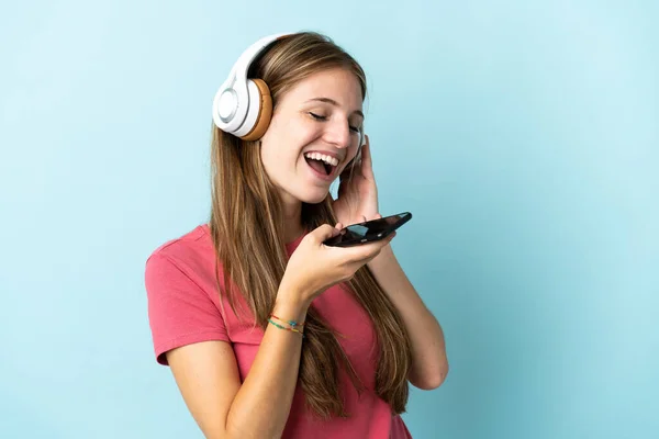 Νεαρή Καυκάσια Γυναίκα Απομονωμένη Μπλε Φόντο Ακούγοντας Μουσική Κινητό Και — Φωτογραφία Αρχείου