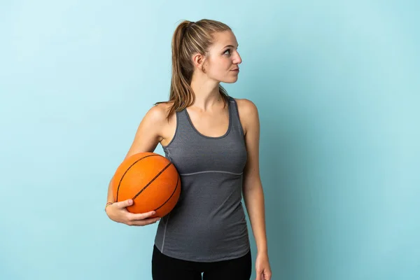 Jovem Mulher Jogando Basquete Isolado Fundo Azul Olhando Para Lado — Fotografia de Stock