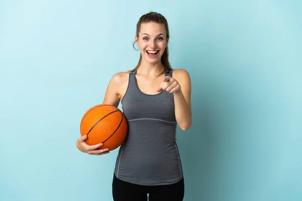 파란색 배경에서 고립된 농구를 여자가 놀라서 앞쪽을 가리켰다 — 스톡 사진