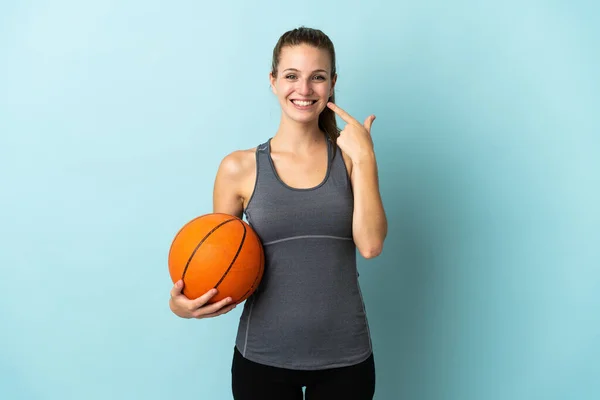 年轻女子打篮球时被蓝色背景隔离了 她举起大拇指做了个手势 — 图库照片