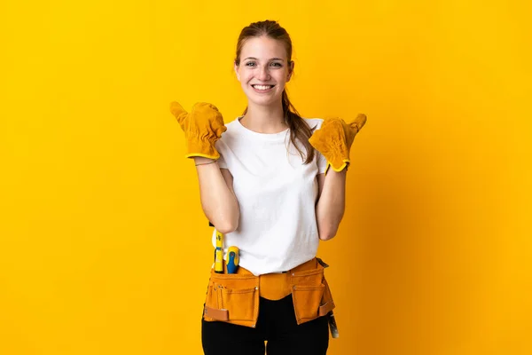 Young electrician woman isolated on yellow background with thumbs up gesture and smiling