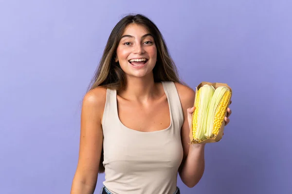 Jovem Segurando Milho Isolado Fundo Roxo Com Surpresa Expressão Facial — Fotografia de Stock