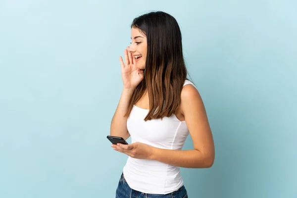 Giovane Donna Caucasica Utilizzando Telefono Cellulare Isolato Sfondo Blu Gridando — Foto Stock