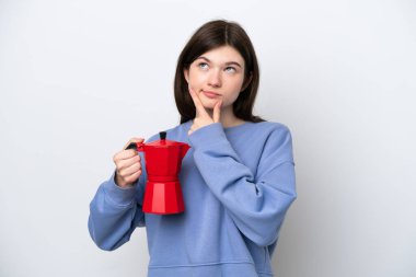 Young Russian woman holding coffee pot isolated on white background having doubts