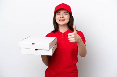 Young Russian pizza delivery picking up pizza boxes isolated on white background with thumbs up because something good has happened