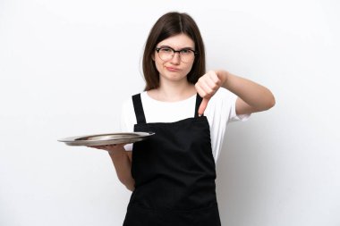 Tepsisi beyaz arka planda izole edilmiş genç Rus kadın aşçı başparmağını negatif ifadeyle aşağı gösteriyor.