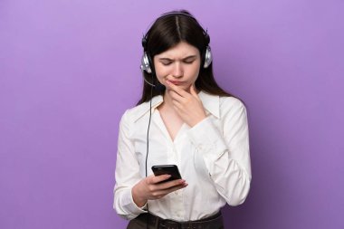Telemarketer Russian woman working with a headset isolated on purple background thinking and sending a message