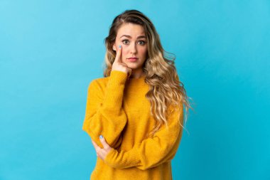 Genç Brezilyalı bir kadın mavi arka planda izole edilmiş bir fikir düşünüyor.