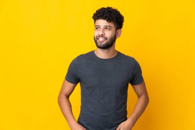 Genç Faslı bir adam sarı arka planda izole edilmiş.