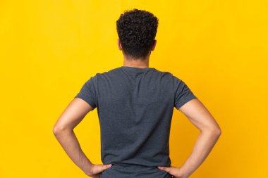 Young Moroccan man isolated on yellow background in back position