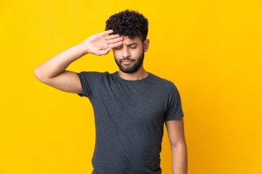 Faslı genç adam sarı arka planda izole edilmiş, yorgun ve hasta bir ifadeyle.