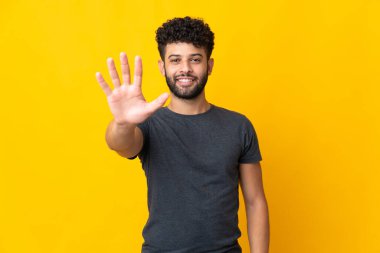 Young Moroccan man isolated on yellow background counting five with fingers