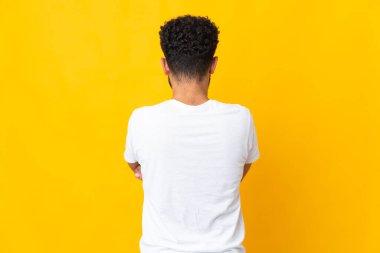 Young Moroccan man isolated on yellow background in back position
